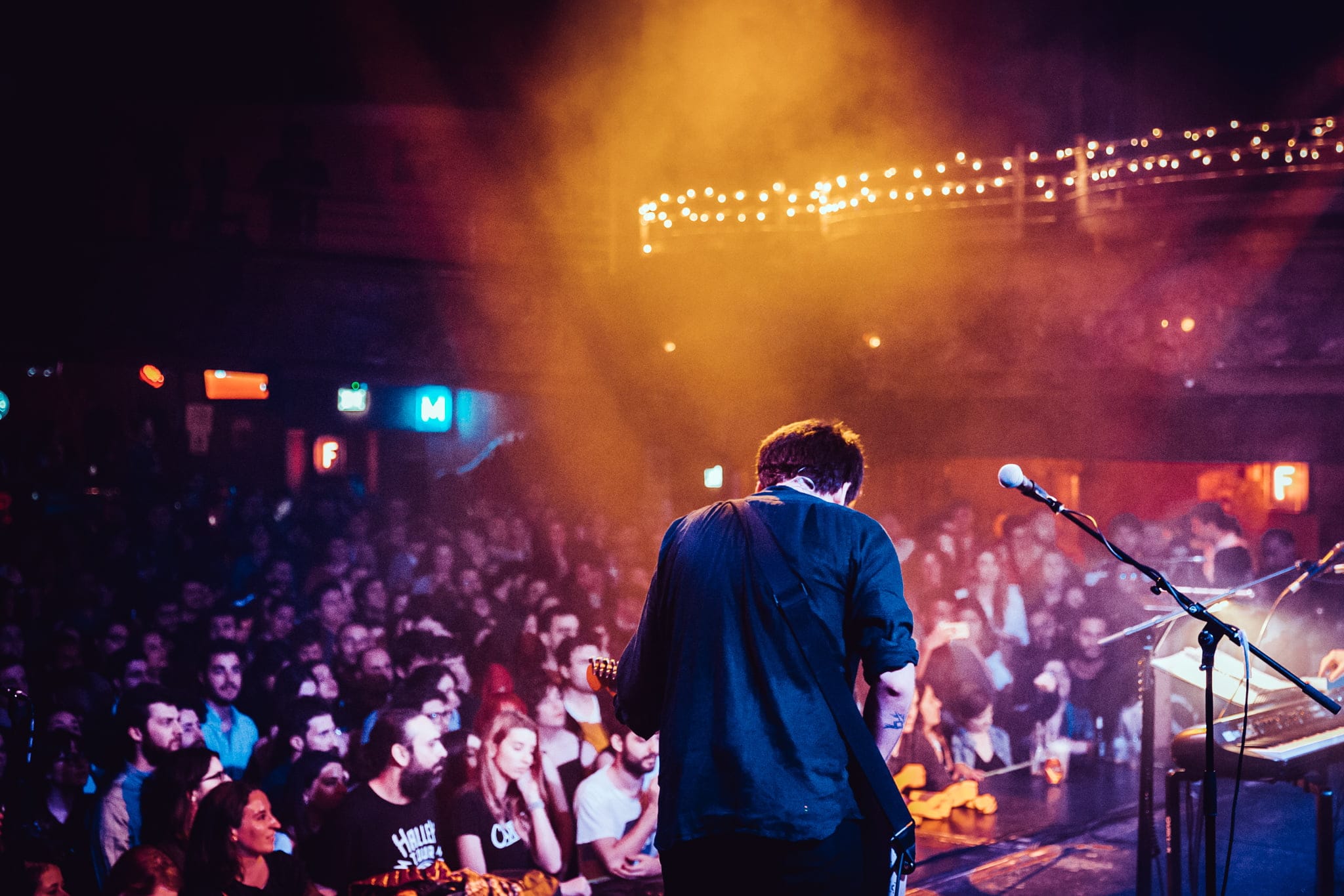 Músico sobre el escenario frente al público en una sala de conciertos.